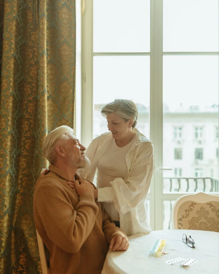 Un couple de retraités à la fenêtre de leur salon