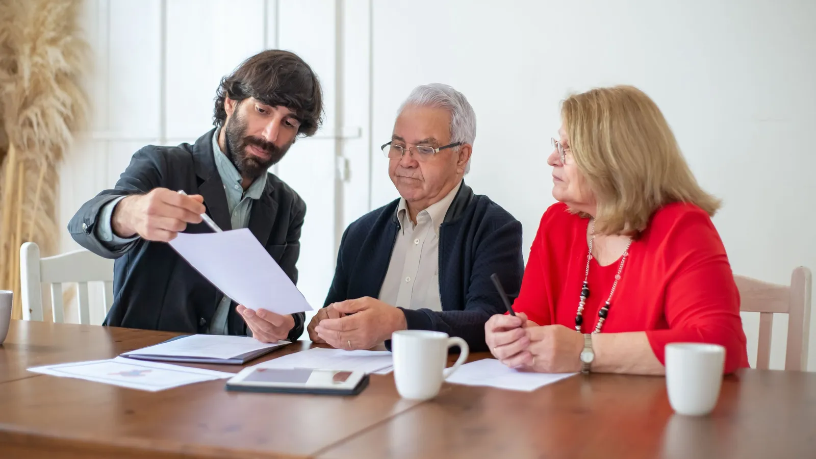 Un couple de seniors examine un document posé sur une table avec un interlocuteur