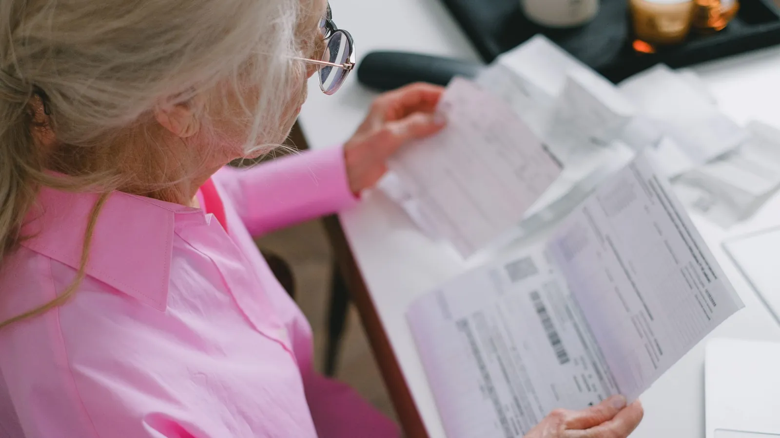 Une femme âgée lit des documents posés sur une table