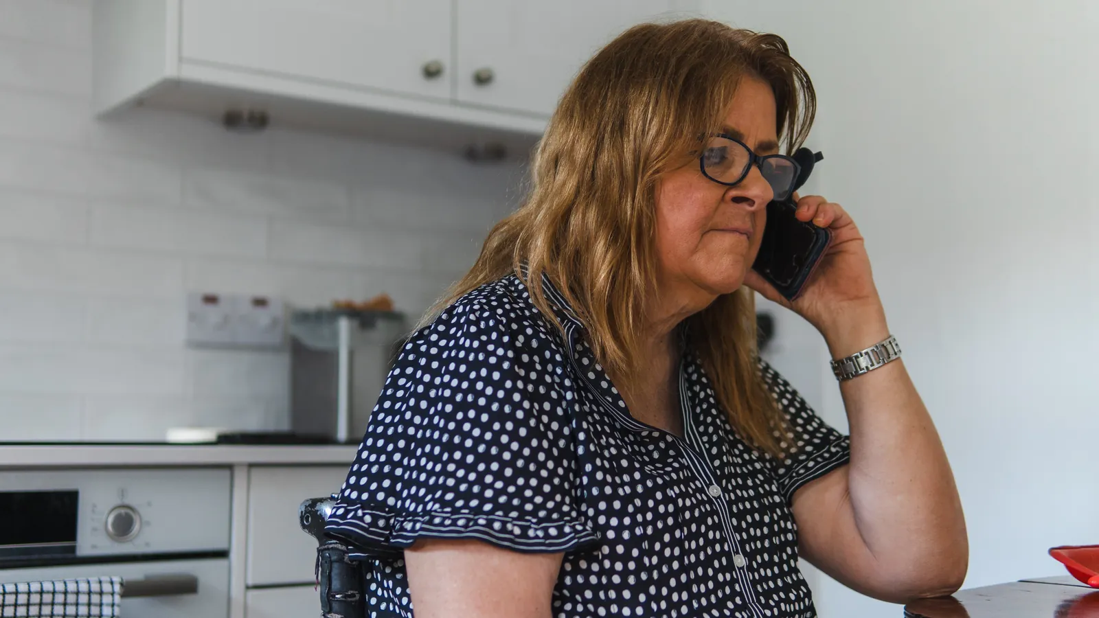 Femme âgée au téléphone dans sa cuisine